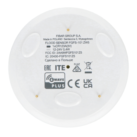 Biały i okrągły czujnik zalania Fibaro leży na białym tle.